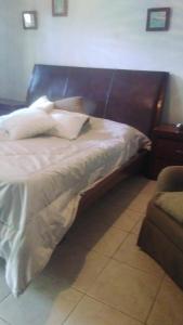 1 cama con cabecero de madera y almohadas blancas en Rincon de ensueño, en Santa Cruz de la Sierra
