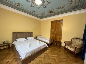 Tiflisi Hostel في تبليسي: غرفة نوم بسرير ابيض كبير وكرسي
