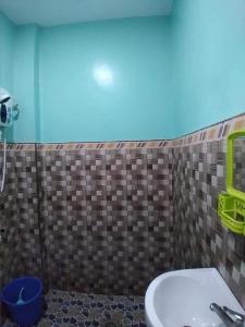 a bathroom with a sink and a tile wall at Azulea Lodging House Oslob in Oslob