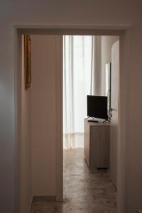 einen Flur mit einer Tür, die zu einem Zimmer mit einem TV führt in der Unterkunft Casa Morrone Residence in Corato
