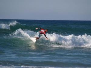 ein Mann, der auf einem Surfbrett im Meer auf einer Welle reitet in der Unterkunft Hotel Estrella del Alemar in Loredo