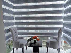 two chairs and a table in front of a large window at Lujoso Apartamento Frente al Estadio Bellavista in Ambato