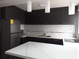 a kitchen with black cabinets and a white counter top at Lujoso Apartamento Frente al Estadio Bellavista in Ambato
