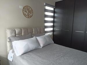 1 dormitorio con 1 cama grande con almohadas blancas en Lujoso Apartamento Frente al Estadio Bellavista, en Ambato