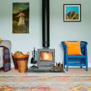 a living room with a fireplace and a blue chair at Number 2 Steading Cottage in Banchory