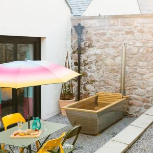 a patio with a table with an umbrella and a tub at Number 2 Steading Cottage in Banchory