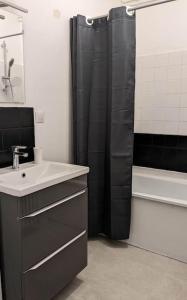 a bathroom with a black shower curtain and a sink at L'Effet-Mer in Dunkerque