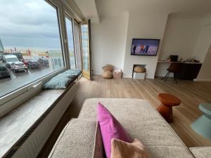 a living room with a couch and a large window at Sunny Seaview in Ostend