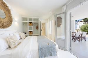 a white bedroom with a large bed and a dining room at VILLA NOSTOS ANTIPAROS in Antiparos