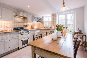 a kitchen with white cabinets and a wooden table at The Way Southwold in Southwold