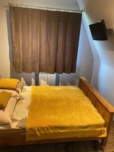 Un dormitorio con una cama con una manta amarilla. en Domek Okno na Tatry - Dom na wyłączność, en Poronin