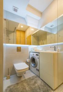 a bathroom with a toilet and a washing machine at Deluxe river view apartment by Polo Apartment in Kaunas