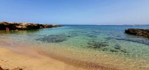 a sandy beach with rocks and the water at Lu Salentu Chalet Beach in Marina di Mancaversa