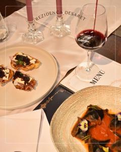 a table with two plates of food and a glass of wine at Hotel Rezidenca Desaret in Berat