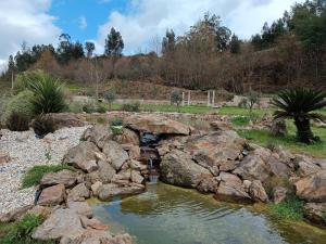 un jardin avec des rochers et un pont sur un étang dans l'établissement Quinta dos Tojais, à Castelbuono