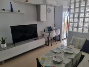 a living room with a flat screen tv and a table at Apartamento Ura in Morro del Jable