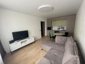 a living room with a couch and a flat screen tv at MB Livinga Vieno miegamojo apartamentai Ventos g in Mažeikiai