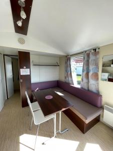 a room with a purple couch and a table and chairs at Team Holiday - Camping du Petit Pont in Arvert