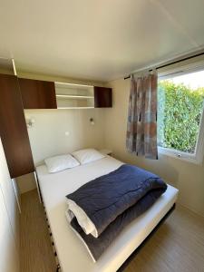 a bed in a small room with a window at Team Holiday - Camping du Petit Pont in Arvert