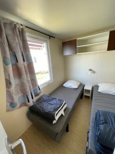 a small room with two beds and a window at Team Holiday - Camping du Petit Pont in Arvert