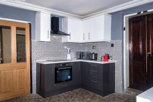 a kitchen with white cabinets and a tv in it at M & B Residence in Freetown