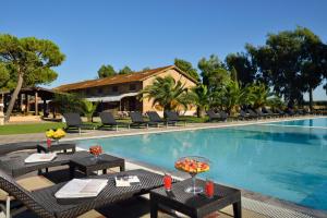 格羅塞托的住宿－凡托利亞聖洛倫索酒店，毗邻度假酒店的带桌椅的游泳池