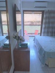 1 dormitorio con 1 cama y 1 mesa con flores en Flat a beira mar, vista lateral - Araça 408, en Natal