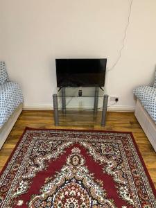 a living room with a red rug and a tv at Ground Floor One Bedroom Bayswater Central London in London