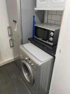 a kitchen with a microwave and a washing machine at Ground Floor One Bedroom Bayswater Central London in London
