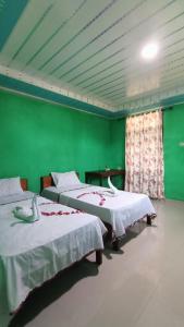 two beds in a room with green walls at Aloha Guest House Nias in Hilibotodane