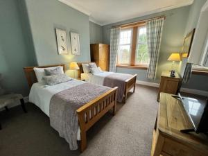 a hotel room with two beds and a television at Pinewood Country House in Leuchars
