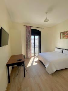 Hotel Mauritania في طنجة: غرفة نوم بسرير وطاولة وتلفزيون