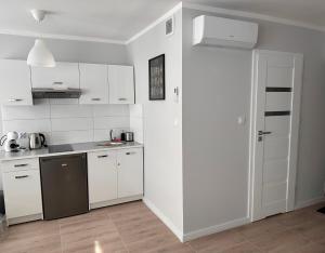 uma cozinha branca com armários brancos e uma porta em APARTAMENT OŚ. ZŁOTE 5F em Dzierżoniów