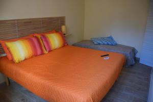 een oranje bed met kleurrijke kussens in een kamer bij La Lanterna di Franca e Cassio in Pisa