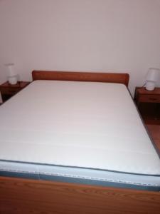 un letto con lenzuola bianche e 2 comodini di asfodelo a Porto Torres