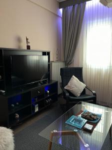 ein Wohnzimmer mit einem TV und einem Glastisch in der Unterkunft Sweet luxury in Thessaloniki