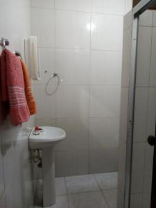 a white bathroom with a sink and a shower at Pousada Tio Sinhô e Tia Sinhá in Rio de Contas