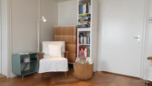a room with a chair and a book shelf with books at Haus an sonniger Lage, schöner Blick auf Alpstein in Urnäsch