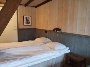 a bed with two pillows in a room with wooden walls at Epokgården in Öregrund
