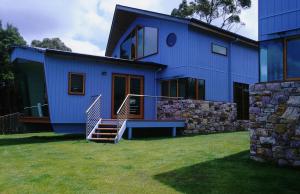 a blue house with stairs in front of it at Wheelhouse Apartments in Strahan