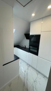 a kitchen with white cabinets and marble floors at Apartament Loft in Elblag