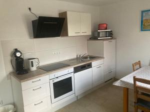 a kitchen with white cabinets and a sink and a microwave at Im Stüble in Koetz 