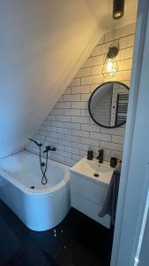 a bathroom with a sink and a tub and a mirror at Apartament Loft in Elblag