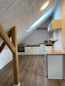 a large room with a kitchen with a vase of flowers on a counter at Nybygget lækker lejlighed. in Kolding