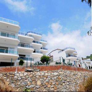 un grand bâtiment blanc avec une clôture devant lui dans l'établissement Sea Wave House, à Alanya