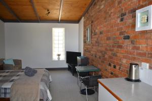 een kamer met een bed en een bakstenen muur bij Colonial Motel in Omeo