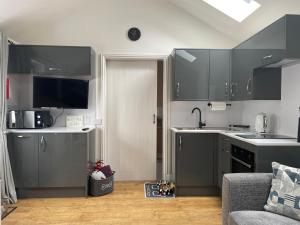 a kitchen with gray cabinets and a sink and a couch at The Old Dairy in Hickling