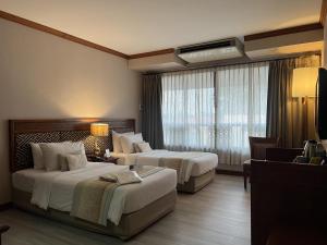 Cette chambre comprend 2 lits et une fenêtre. dans l'établissement Tohsang Heritage Ubon Ratchathani Hotel, à Ubon Ratchathani