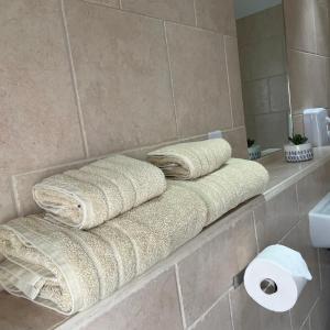 a bathroom with three towels and a roll of toilet paper at The Old Dairy in Hickling