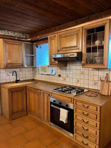 a kitchen with wooden cabinets and a stove top oven at Monolocale rustico di montagna in Antey-Saint-André